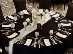 A table set with black and white plates, silverware, and napkins.