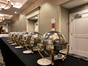 A row of silver chafing dishes on top of a black table.