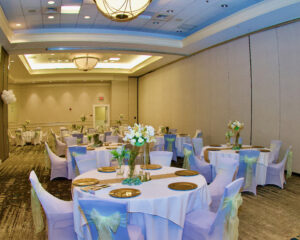 A hall full of chairs and table with decorations and flowers.